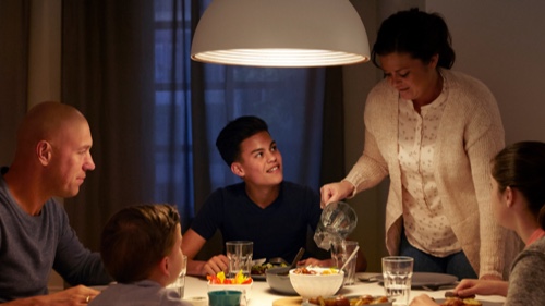 Evde iyi aydınlatılmış bir yemek masasında yemek yiyen aile